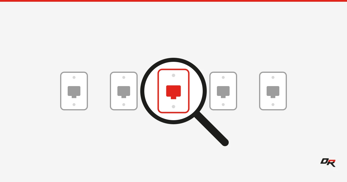 Five gray wall-jack faceplates in a row on an off-white background, with a black magnifying glass held over the center plate, which shows red inside the lens.